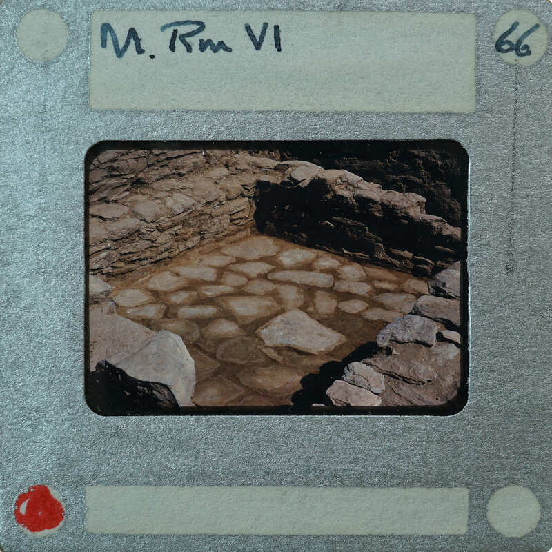 An old photograph of a stone structure with a visible number and handwritten name on the border.