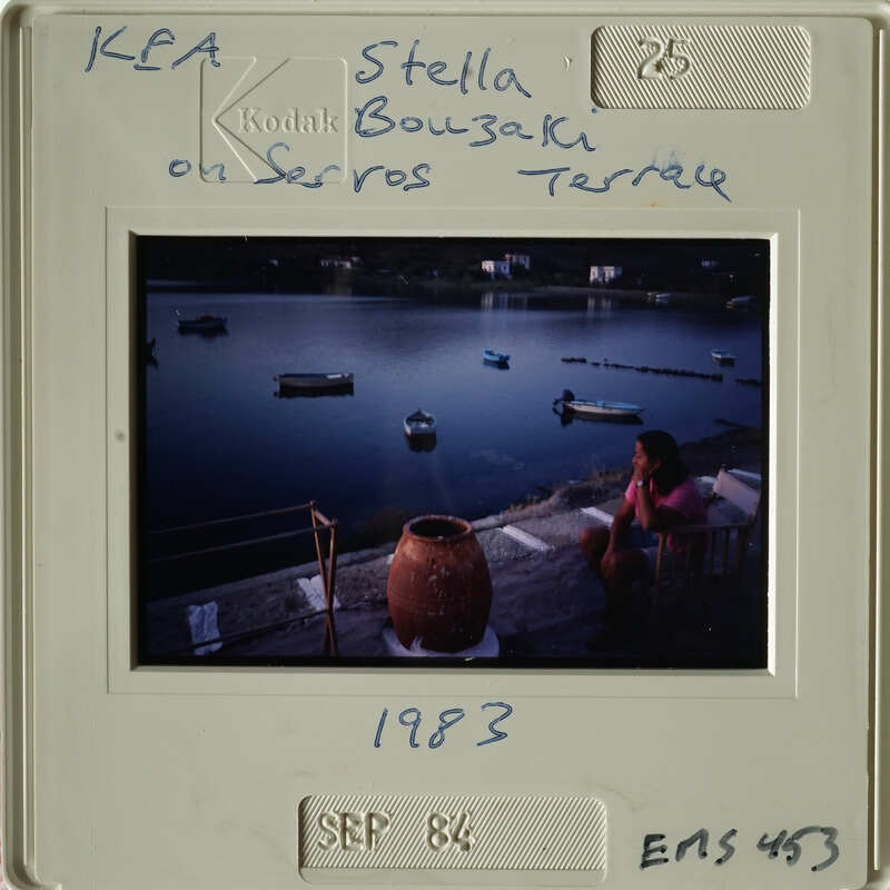 A woman sitting at a table with a view of boats on water, dated September 1983.