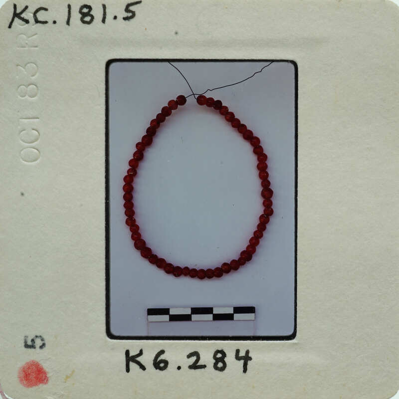 The image shows a red bead bracelet on a white background.