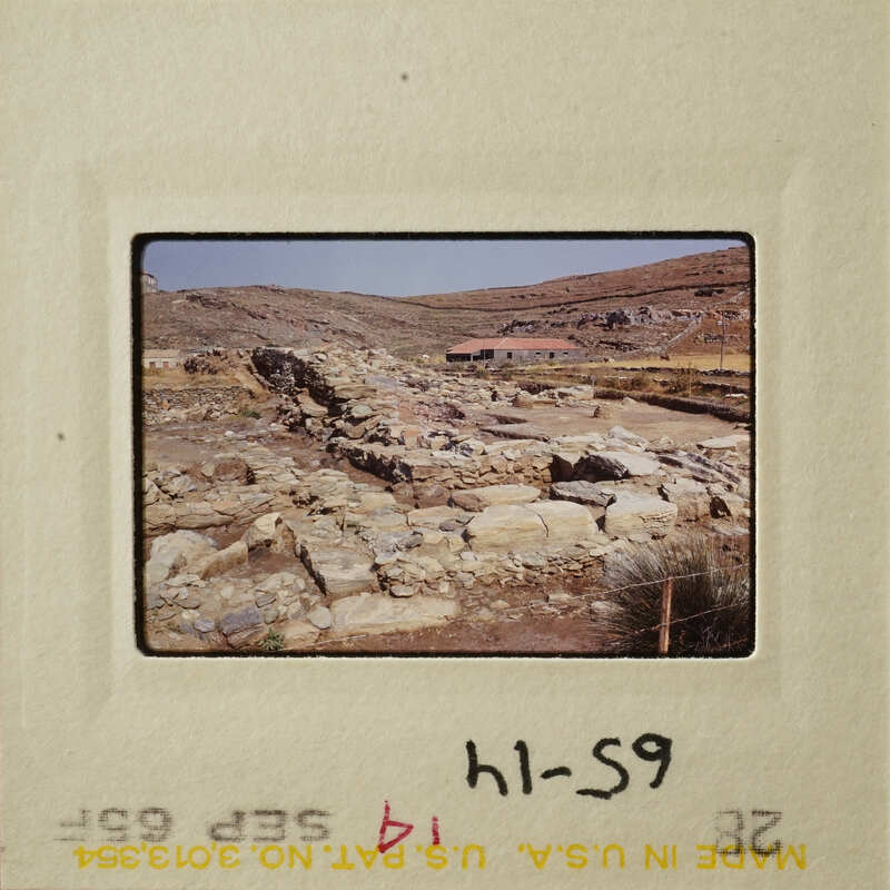 Ruins of an ancient stone structure with a clear sky and mountains in the background.