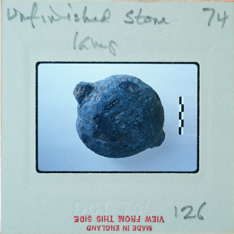 A small, round blue object with a rough texture on a white surface.