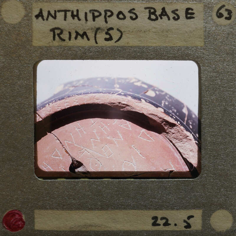 Ancient clay pot with writing on its side, displayed in an exhibition setting.