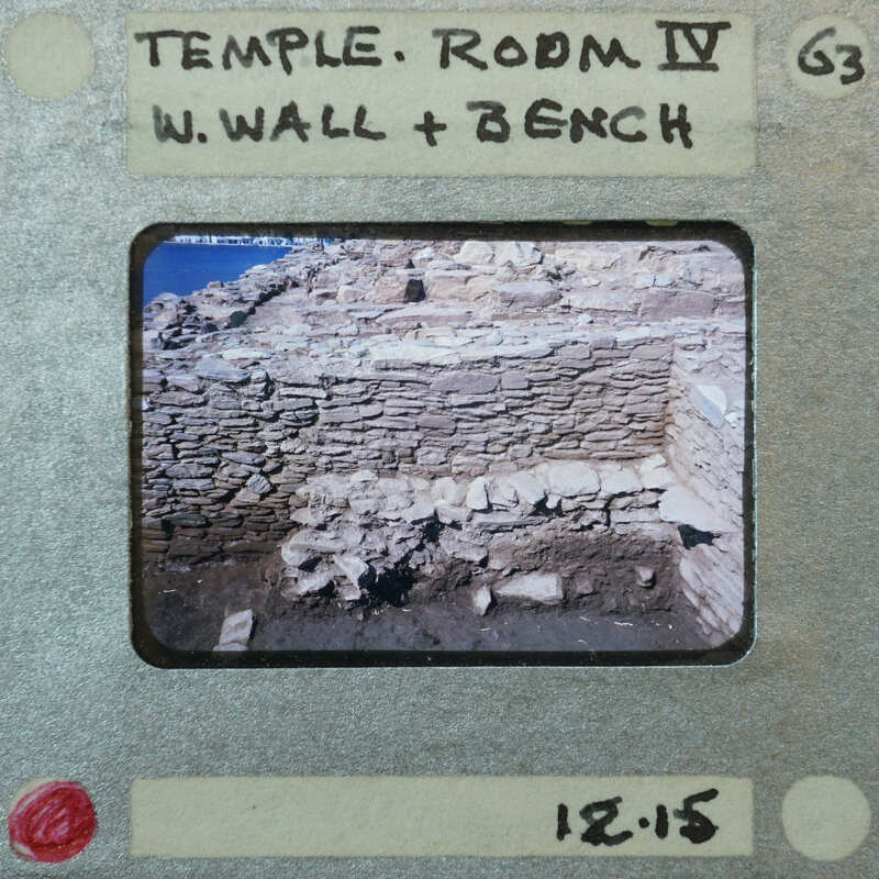 Detail of tall stone wall with smaller stone wall in front in fragmentary condition.