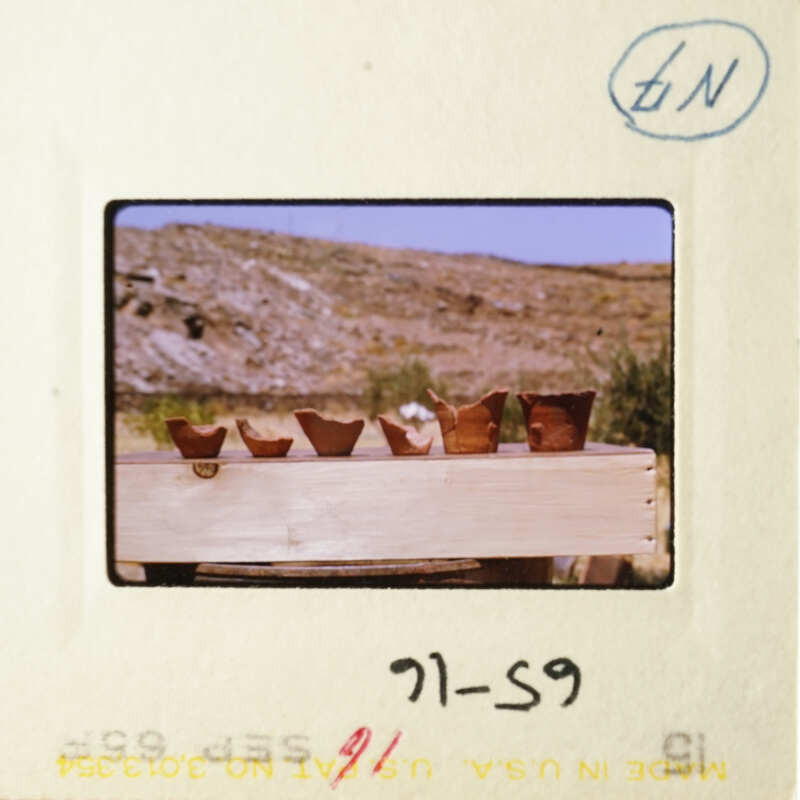 A photo of pottery on display, with a mountainous landscape in the background.