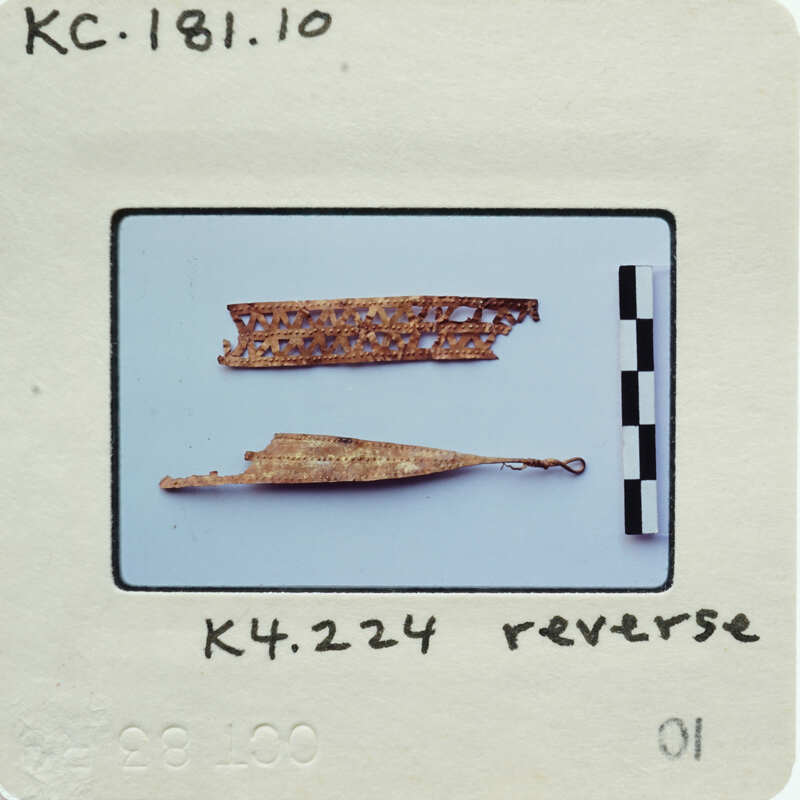 Two small, gold-colored artifacts with intricate designs on a white background.