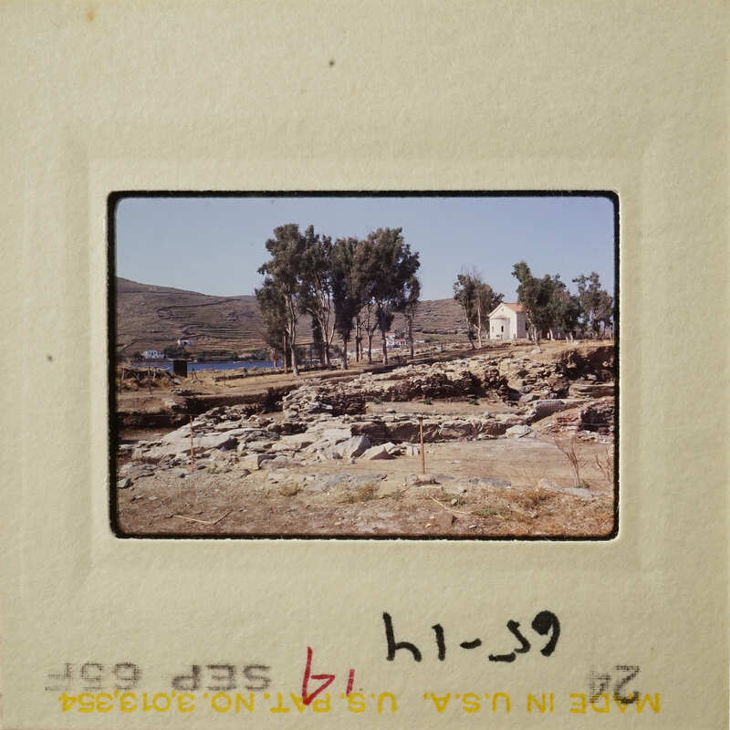 A photograph showing an outdoor scene with trees, ruins, and a clear sky.