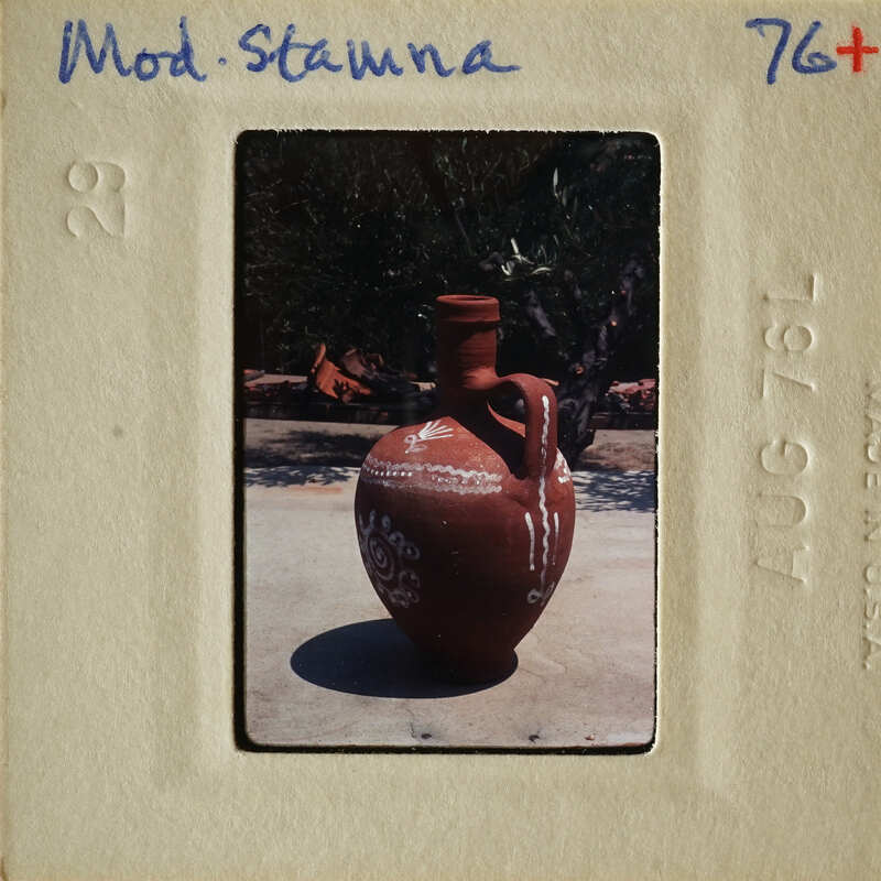 A clay vase with decorative patterns on a concrete surface.