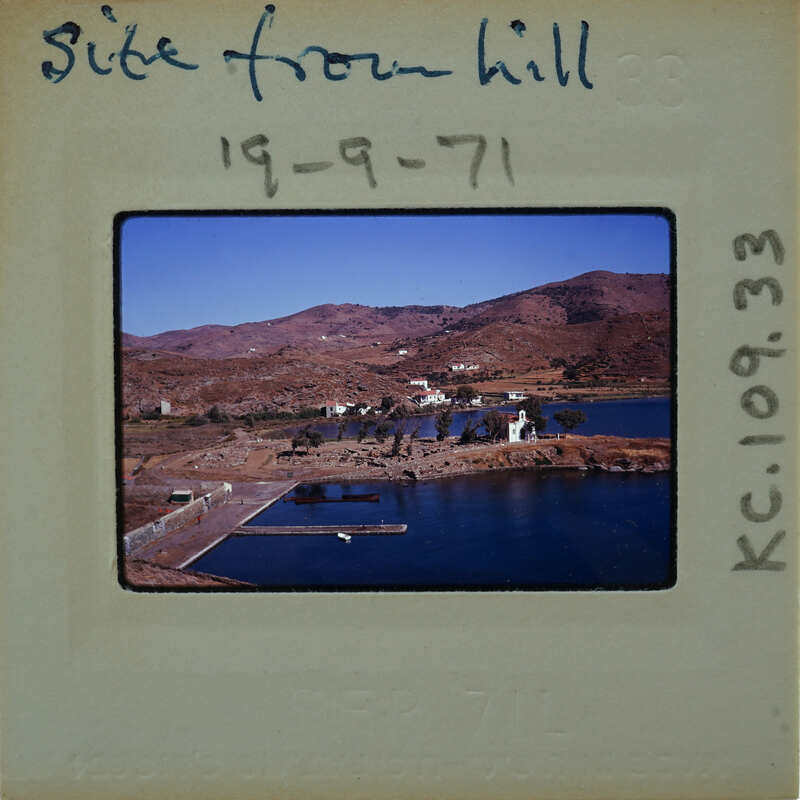 A vintage photo of a scenic coastal landscape with mountains, water, and buildings.