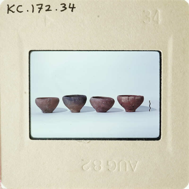 Row of four clay pots on a white surface.