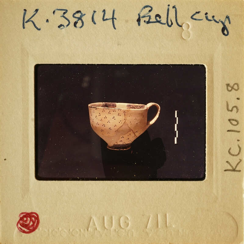A photograph of an antique cup on a white card with handwritten details and a red stamp at the bottom.