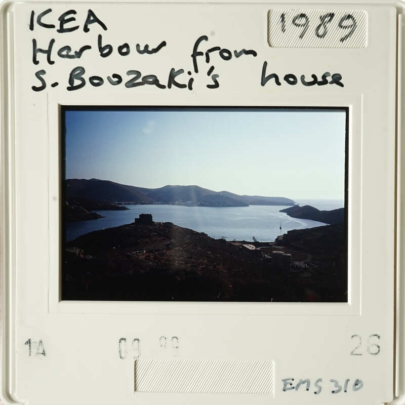 View from S. Boouzaki's house, showing a serene lake and mountain landscape with a clear sky.