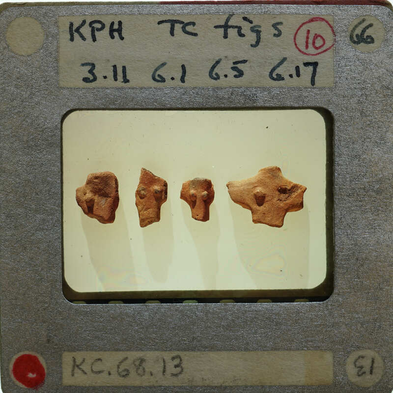 Four small clay figurines on a display stand with labels.