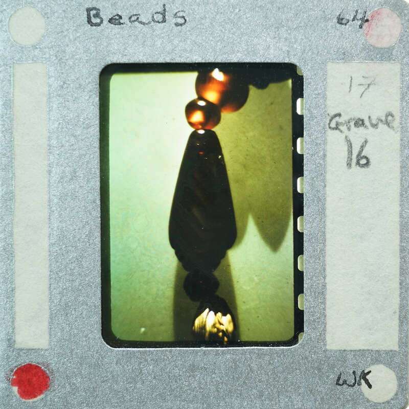A photograph of a necklace detail with beads on a film strip.