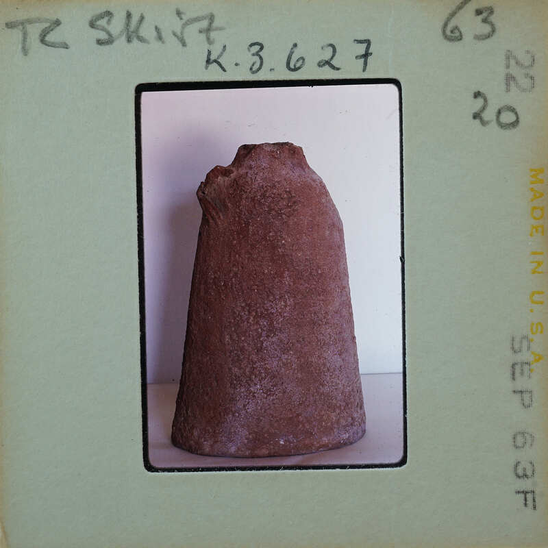 A photograph of a brown pottery item with a handle, displayed on a white surface.