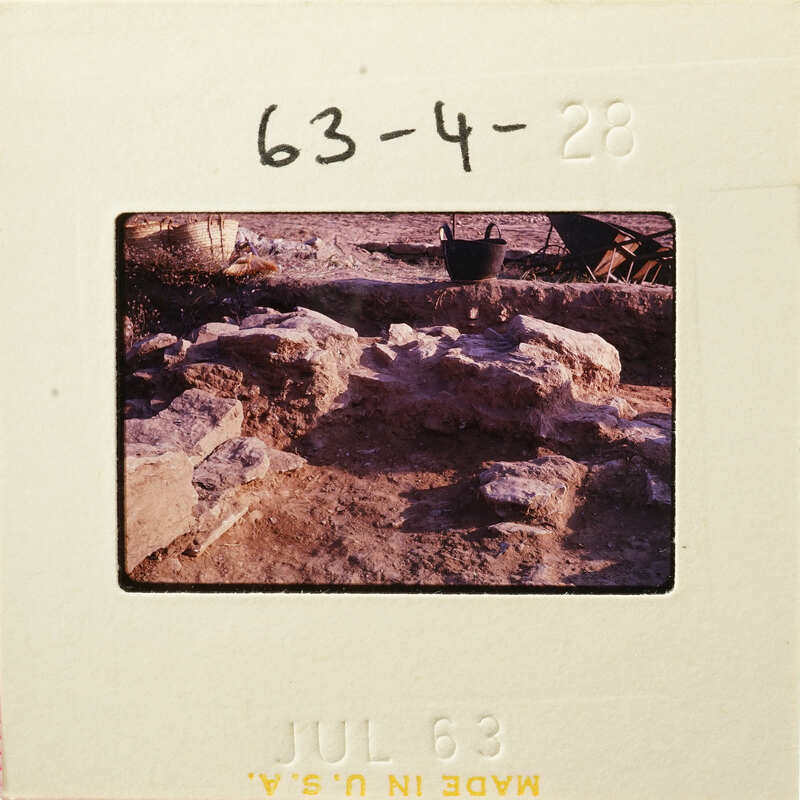 Old photograph showing an archaeological site with stone ruins and dirt ground.