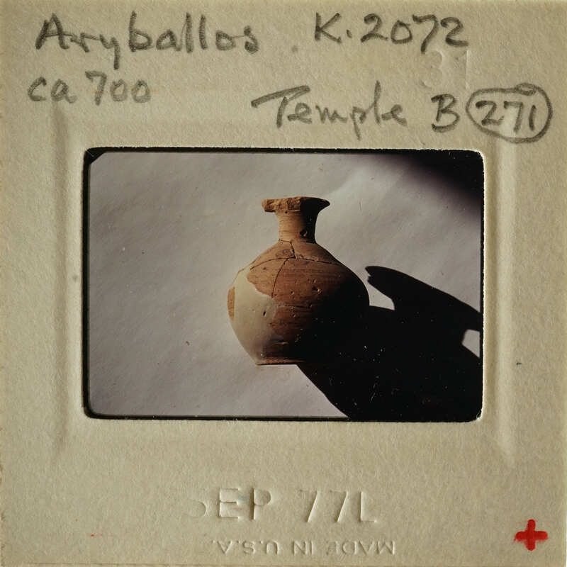 Ancient clay pot on display with handwritten notes and numbers indicating its origin and identification.