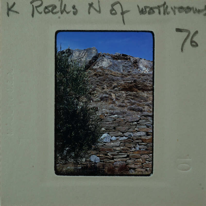 A photograph of a stone wall with mountains in the background, on film strip labeled "76".