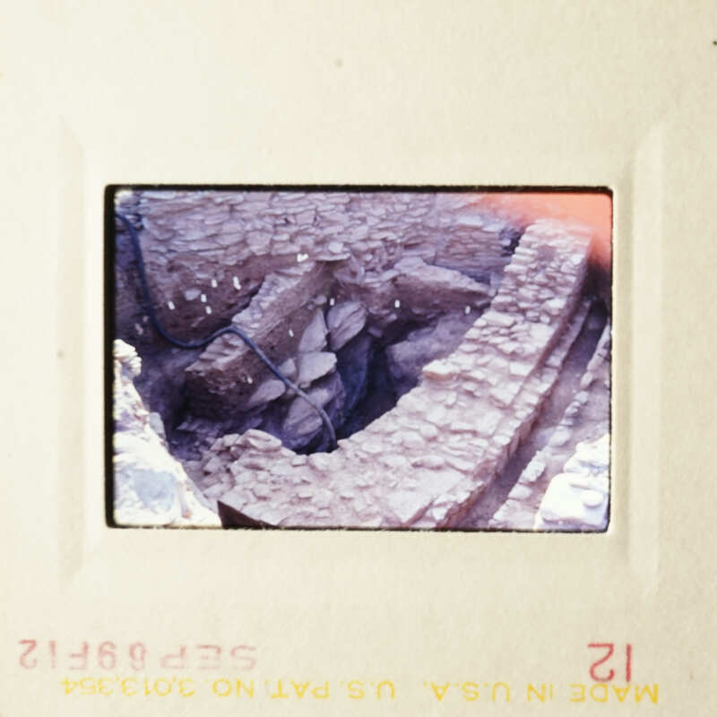 The photo shows a damaged structure, possibly an old building or wall, with visible stonework and cracks.