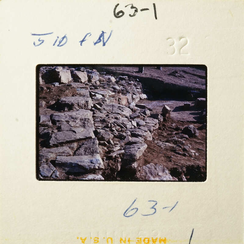 A photograph of an ancient stone structure, possibly ruins, with a focus on its layered and weathered rock walls.