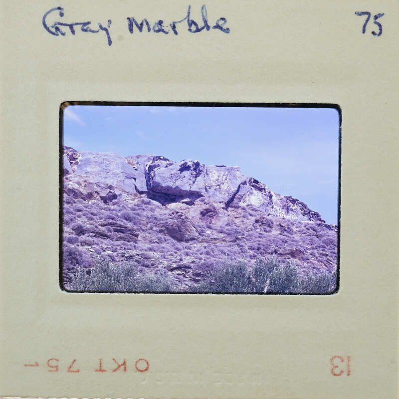 A vintage photograph of a rocky mountain landscape with a film strip label reading "Grey Marble" and number 75.