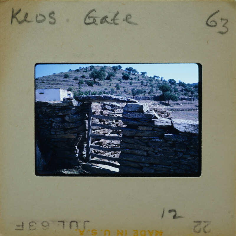 A photograph of a stone structure, possibly ruins or an old building, with a mountainous landscape in the background.