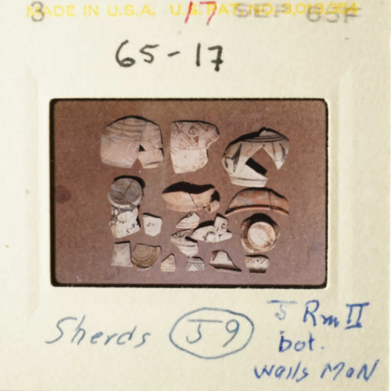 This is an image of a collection of broken pottery shards, with some pieces larger and more intact than others, displayed on a table.