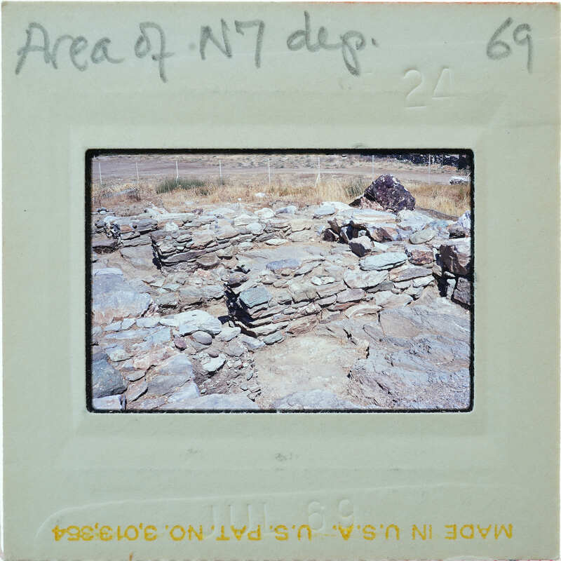 The image shows an old, crumbling stone structure with a dirt ground and sparse vegetation.