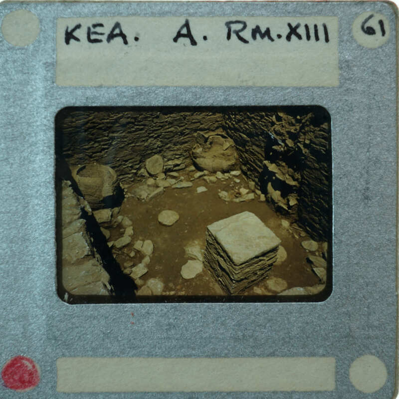 A photograph of an old, stone-walled room with a pile of rubble and rocks in the center.