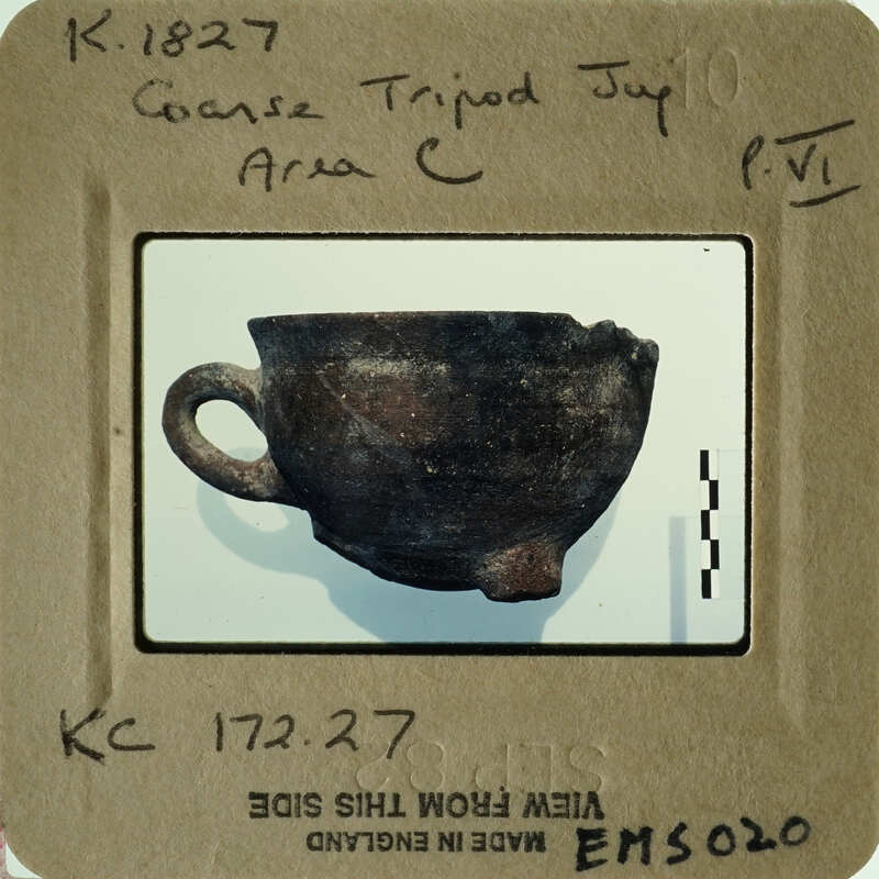 Ancient pottery displayed on a white surface with a label and barcode.