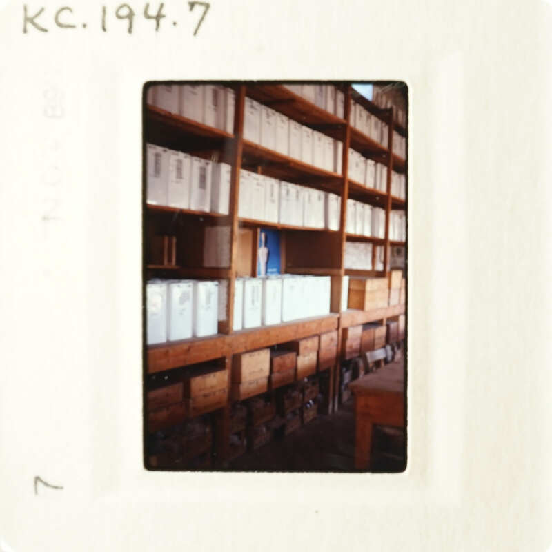 A photograph of an indoor setting with numerous file cabinets and shelves filled with files, taken from a low angle.