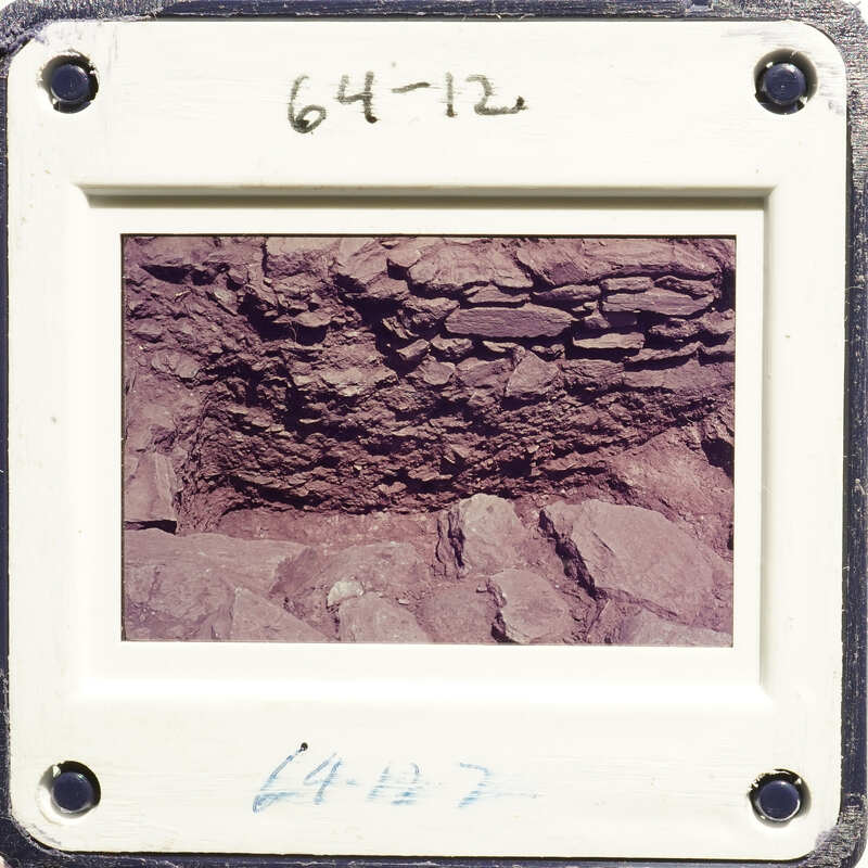 A photograph of an old rock formation with layers and crevices, taken from a low angle.
