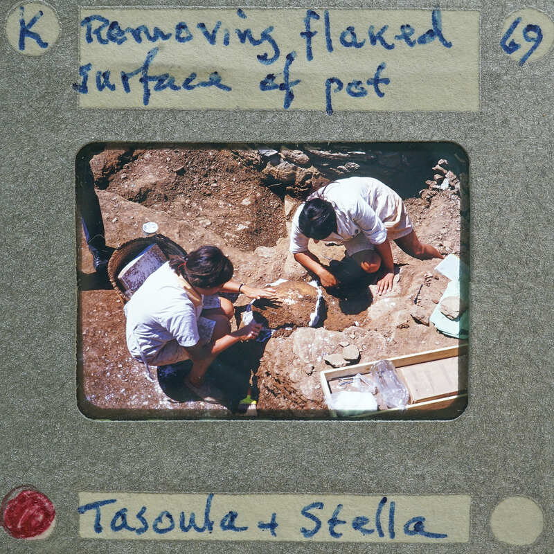 Three archaeologists working on a site, examining and removing pottery from the ground.