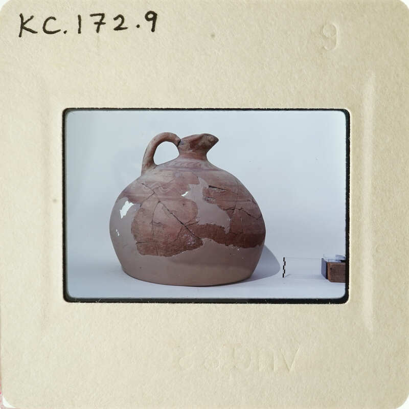Ancient clay pot with visible cracks and earth tones, photographed against a light background.