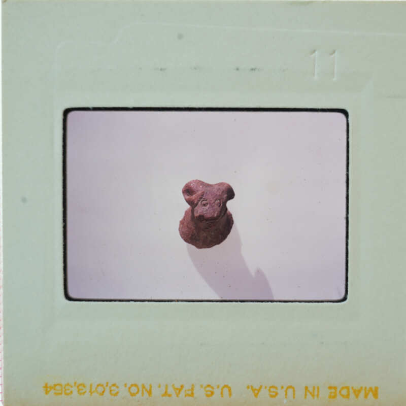 A small, brown dog figurine on a white surface with a shadow cast behind it.