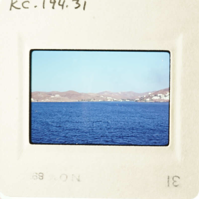 This is an image of a serene blue ocean with mountains in the distance, captured on a photographic slide.