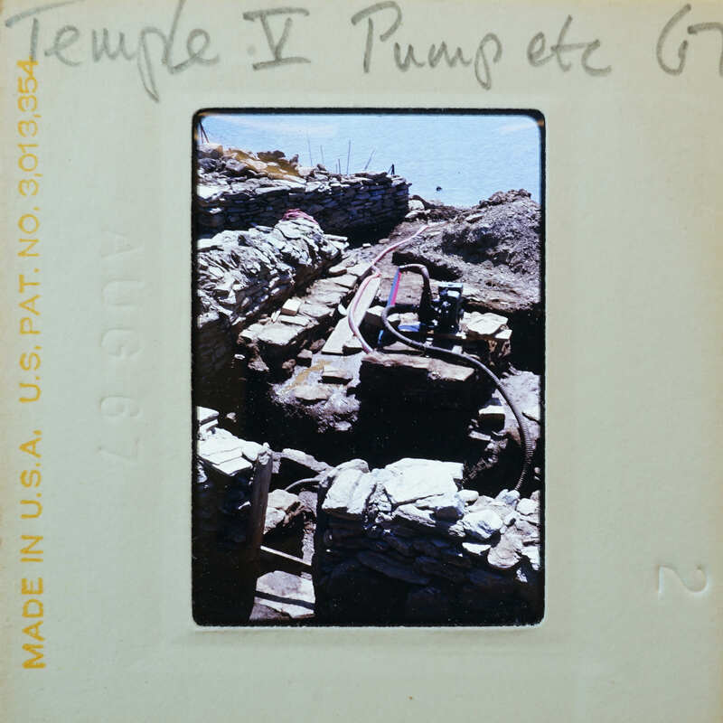 Various stone walls with pump hose running from a building to the sea.