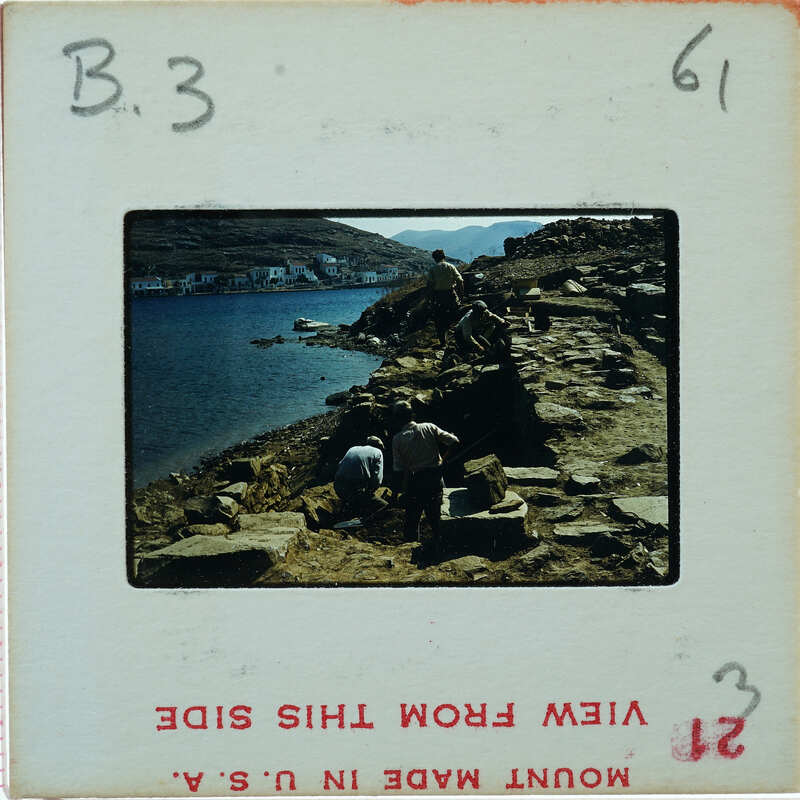A vintage photograph of a rocky coastline with people working on stone construction.