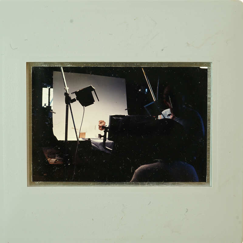 A person sitting at a desk with lights and equipment, possibly in a studio setting.