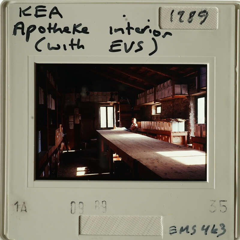 A photograph showing an interior room with wooden benches and tables, possibly used for meetings or gatherings.