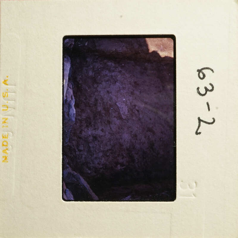 An antique photograph with an illegible date and location stamp on its border, depicting a blurred scene within a dark interior.