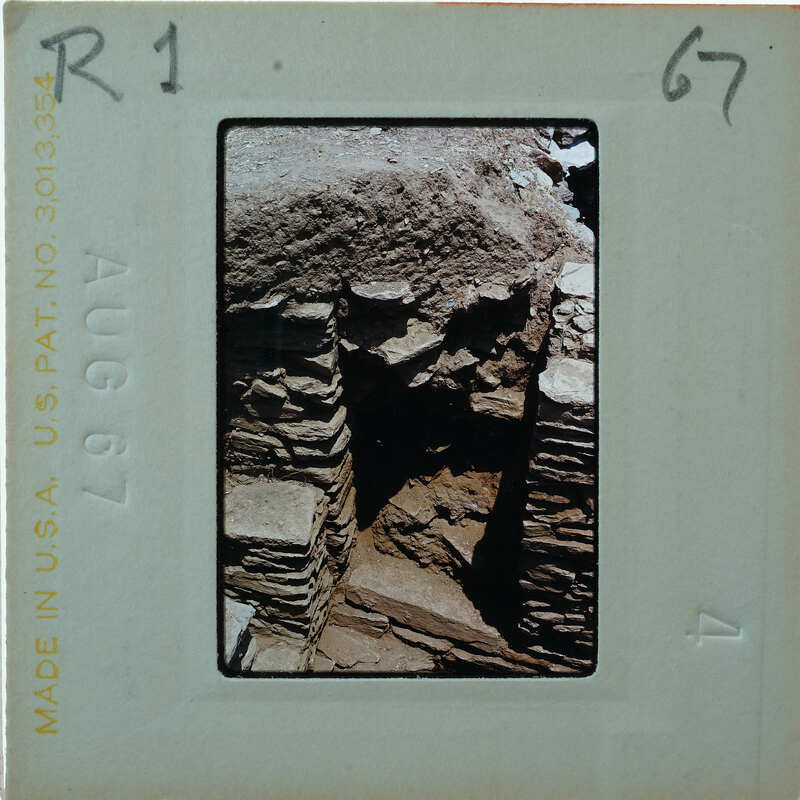 Old stone ruins with a focus on the crumbling wall and archway, possibly from an ancient civilization or historical site.