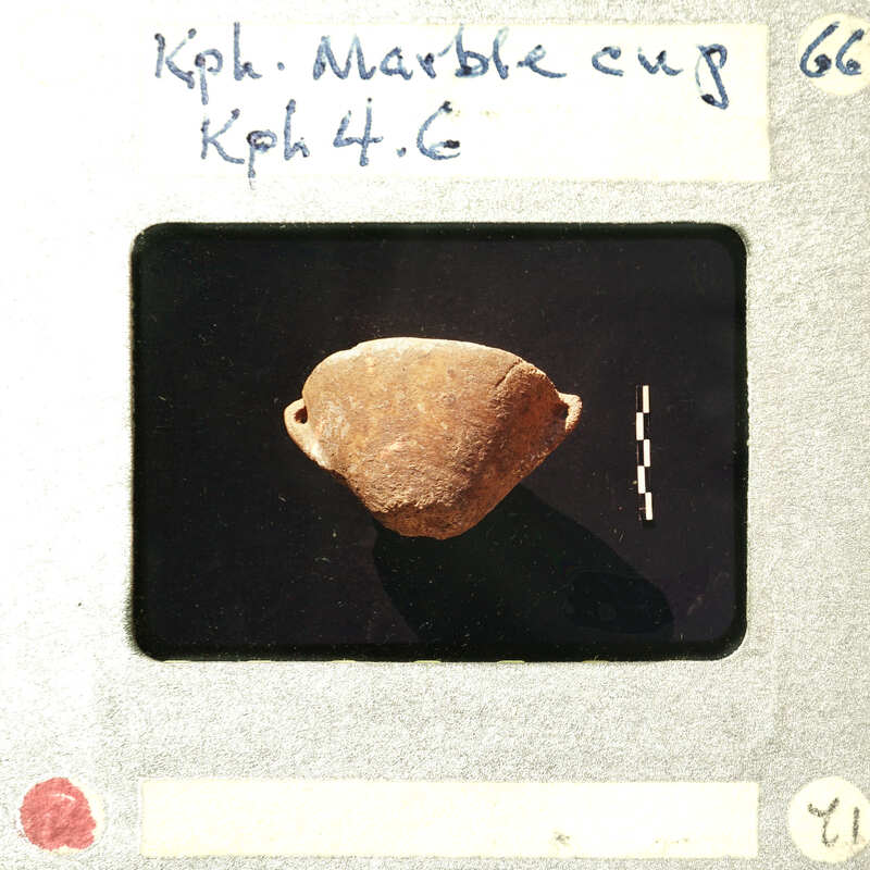 A small, round, ancient object on display with a label and information card.