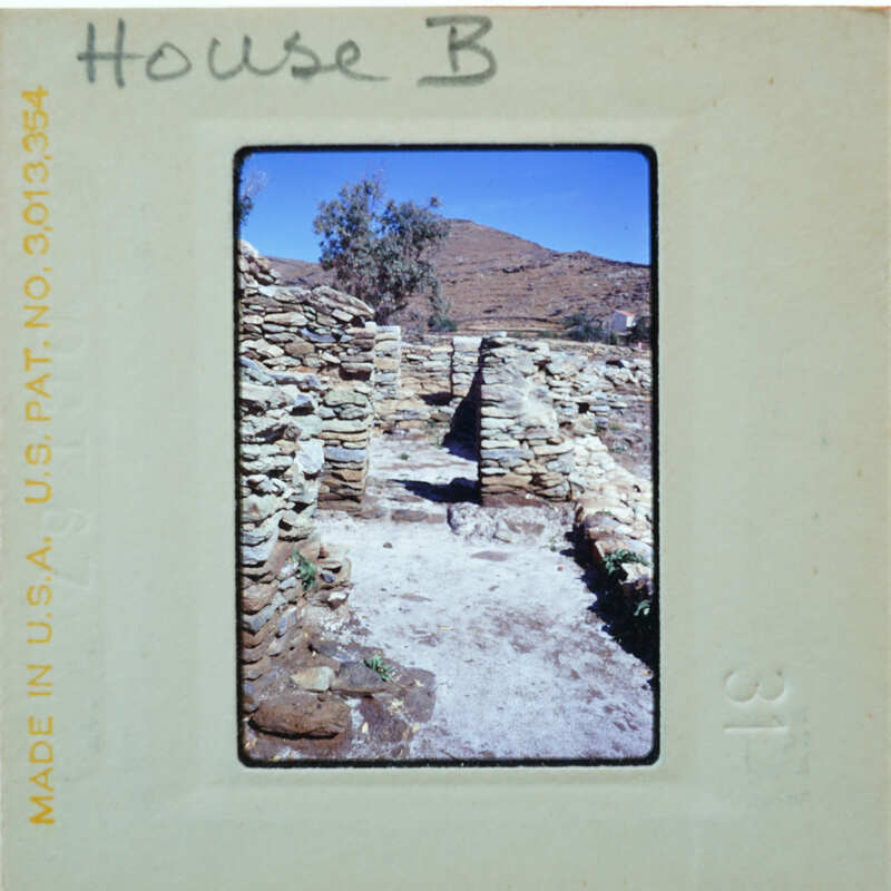 Old stone ruins with a blue sky and mountains in the background, photographed on an old film strip.