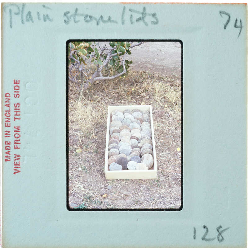 A wooden box of stone discs on the ground.