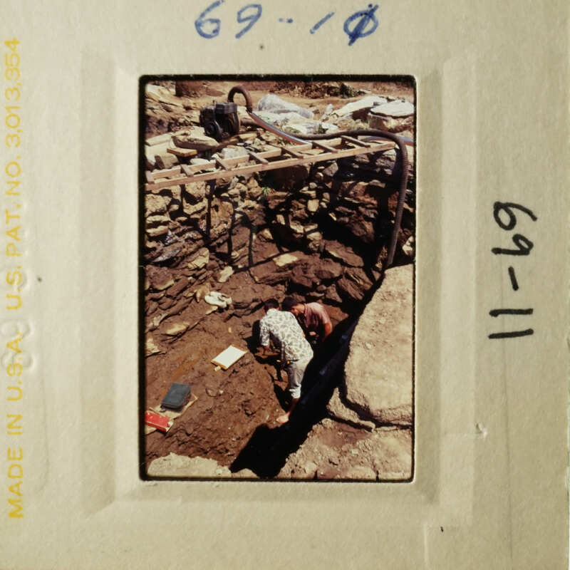 A man working on an archaeological site, surrounded by tools and materials.