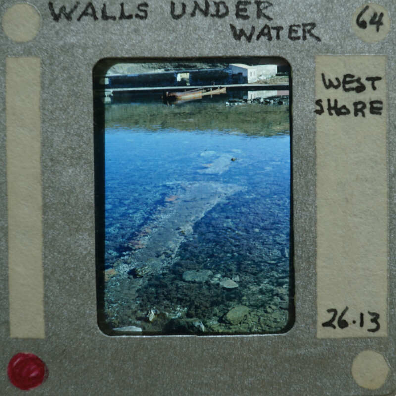 A photograph of a shallow body of water with rocks and debris, enclosed within an old-fashioned film strip frame.
