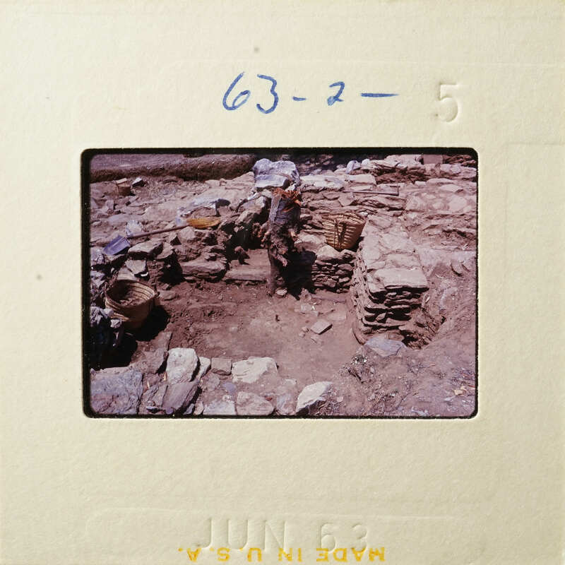 This is an old photograph showing ruins with stones and debris, possibly from an archaeological site.