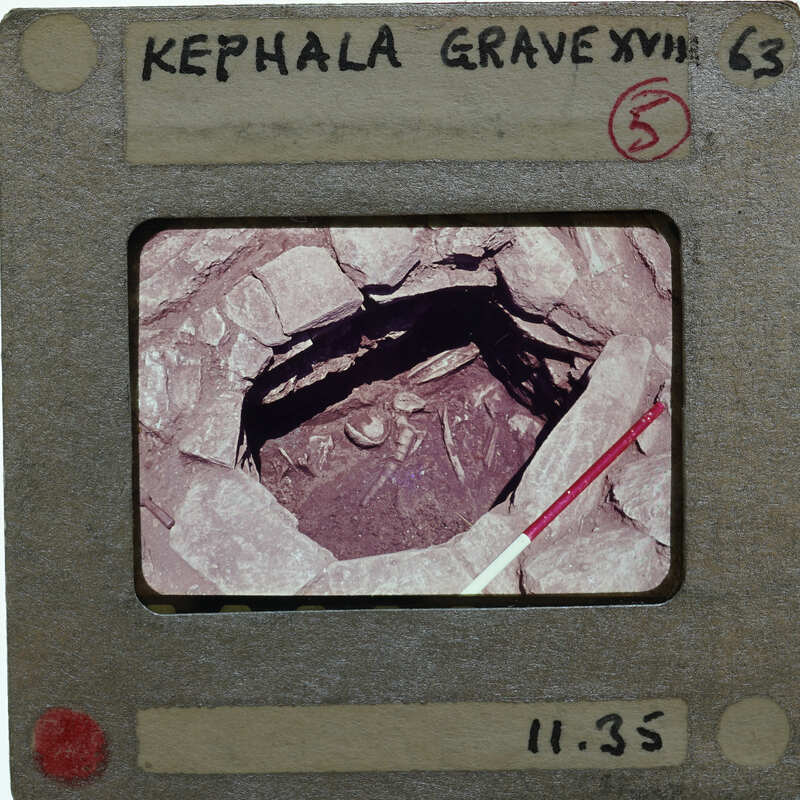 A hole surrounded by stones, with burial remains at the bottom.