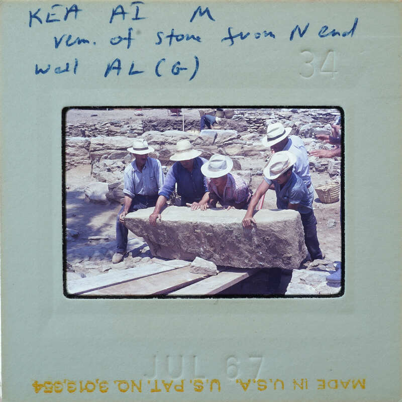 Four men working on a large stone block at an archaeological site.