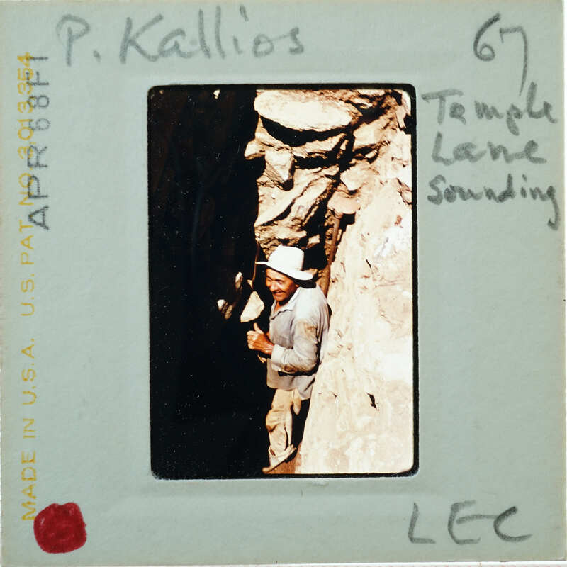 Man standing next to a rock wall with a temple entrance.